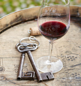 EIn Beispiel aus der Foto-Reportage: Ein Glas Wein und zwei Schlüssel liegen auf einem Holzfass